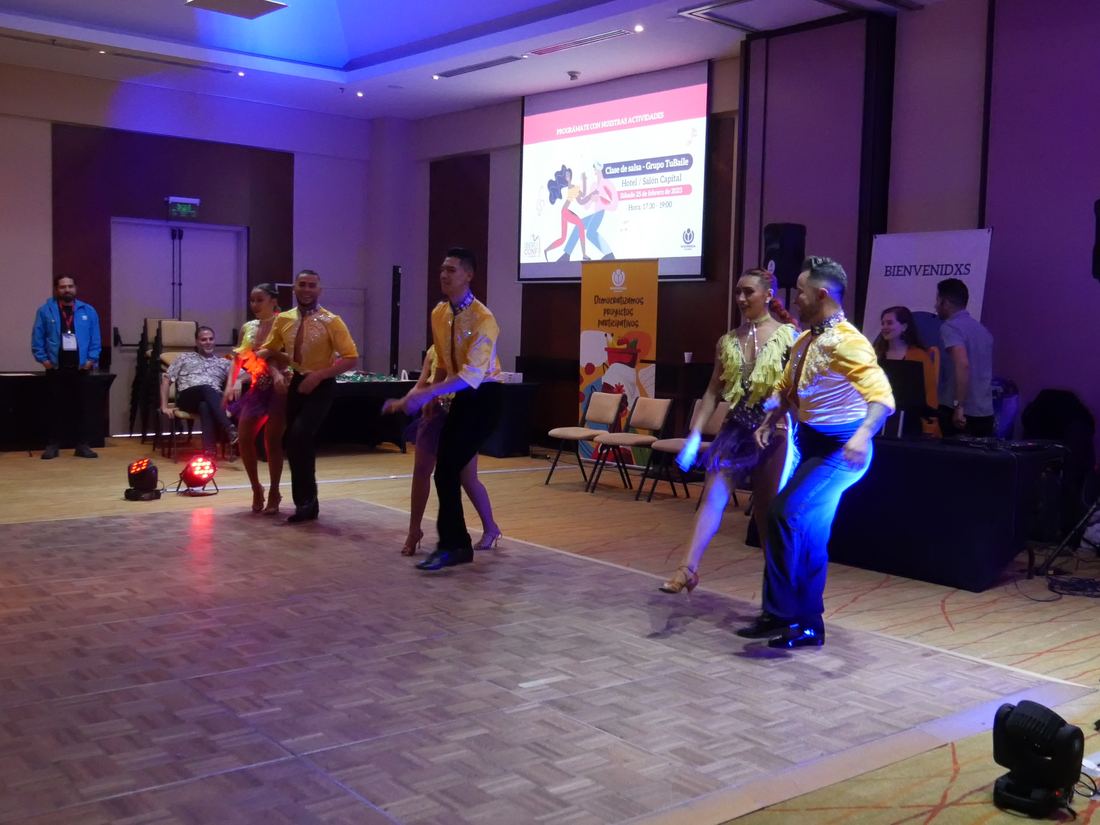 Students follow a salsa instructor in a dimly lit hall